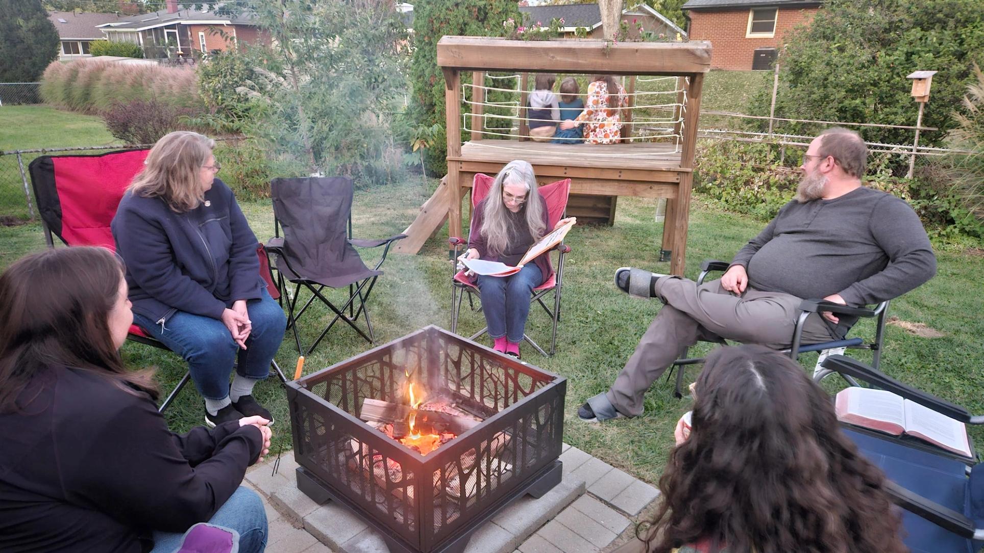 A Life Group meets around a back-yard fire pit, Bibles open on their laps