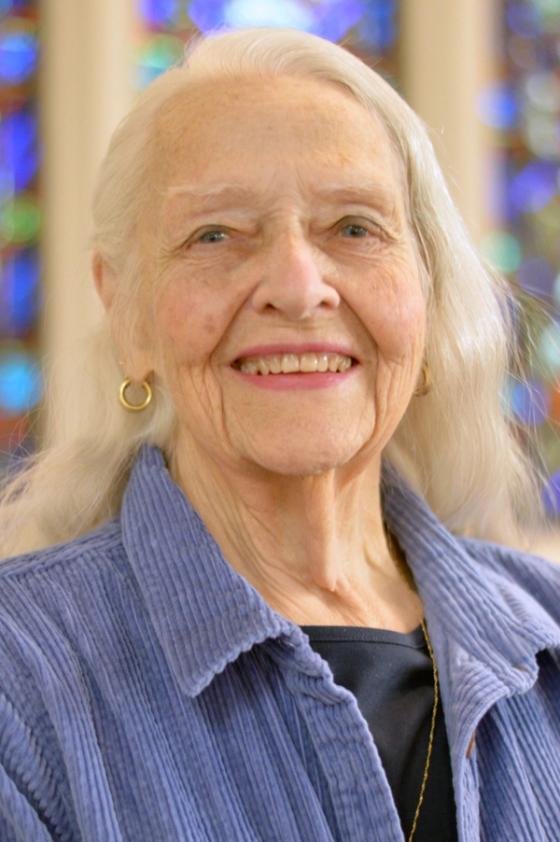 Dana Davis, an older woman, smiling, a stained glass window behind her.
