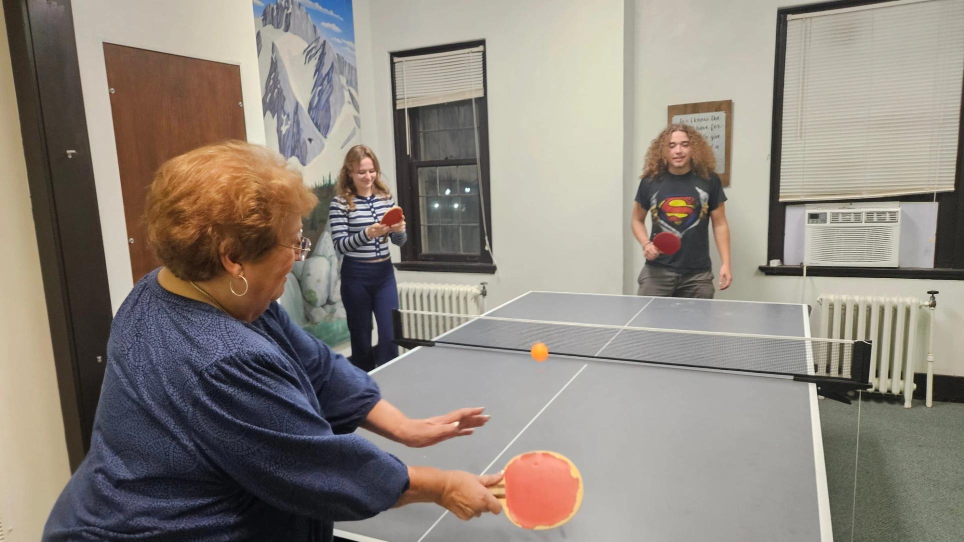 A church member takes on two teenagers at ping pong in the youth room