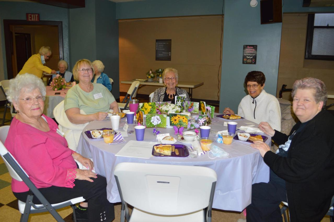 Women of the church sit together at a round table set for a fellowship breakfast.