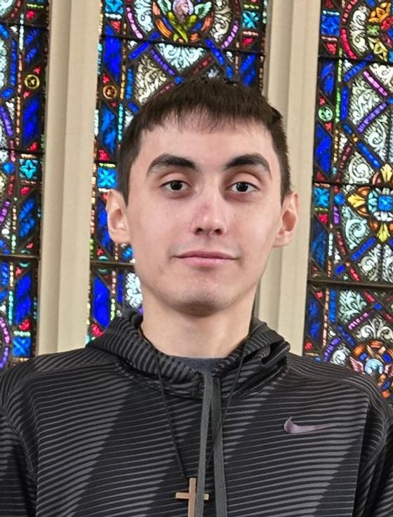 Andy Heimlich, a young man in a hoodie, in front of a stained glass window.