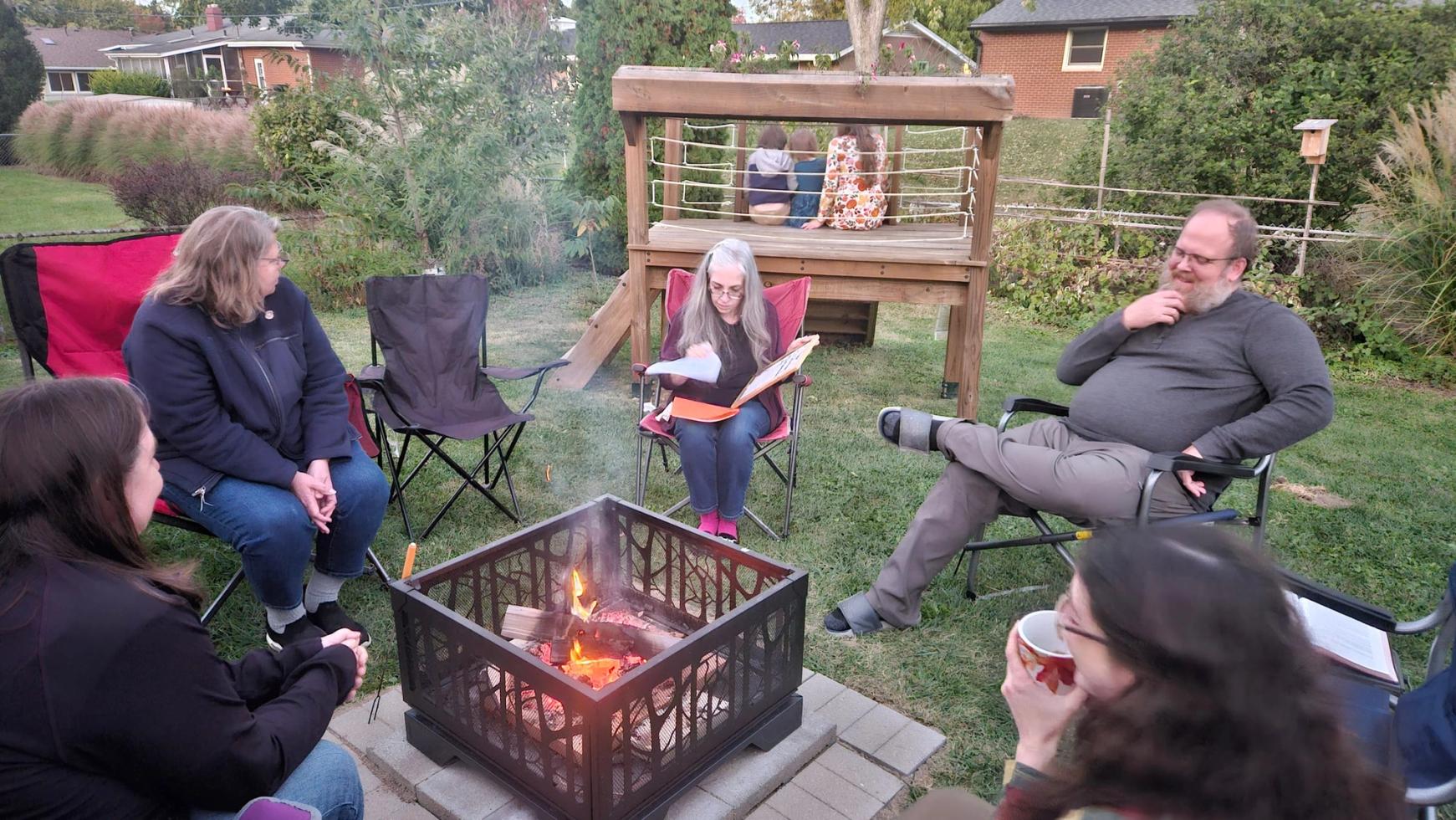 Members of a Life Group talk and laugh around a back-yard fire on an autumn evening