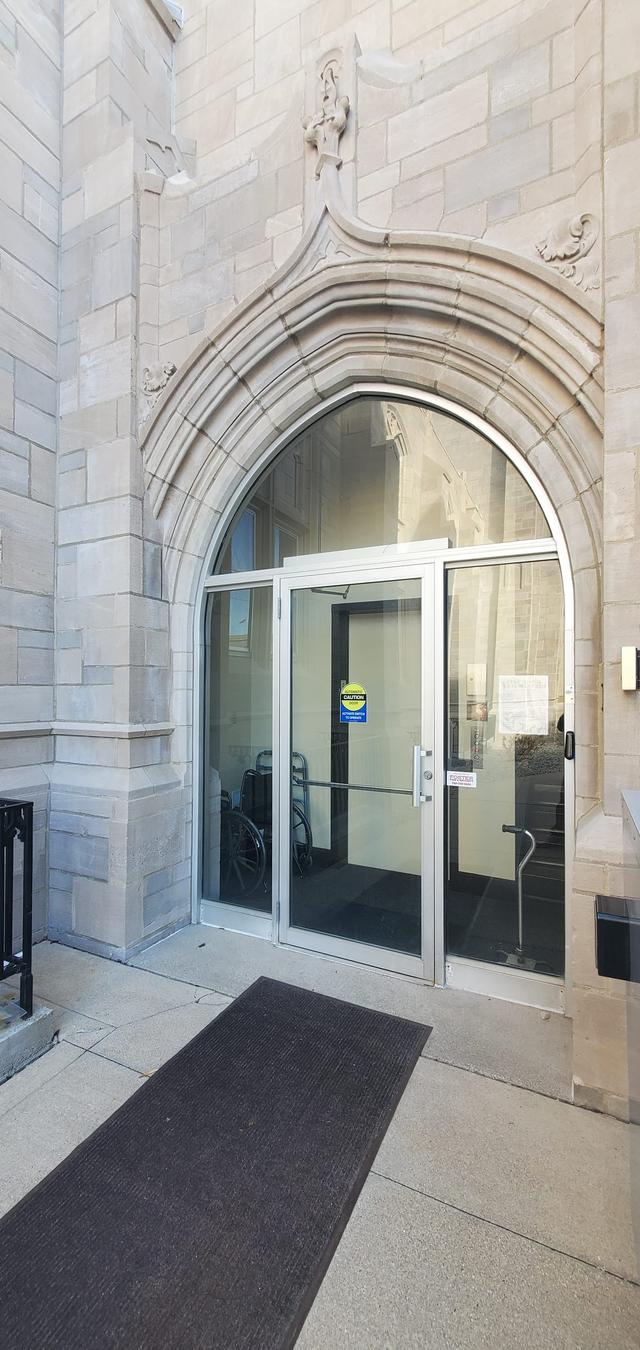 A pair of glass entry doors sit beneath a carved stone archway at the church entrance.