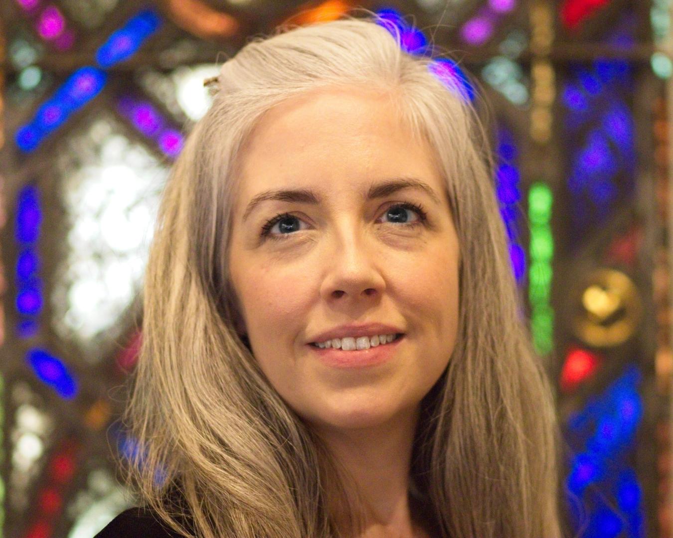 Cynthia Smith smiling, a stained glass window behind her.