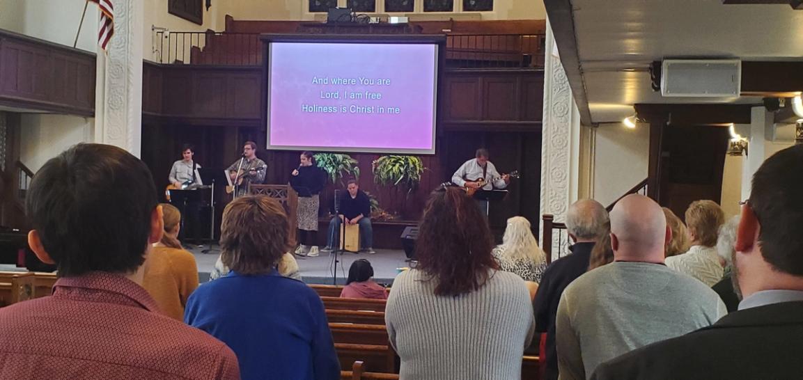 The congregation standing in the sanctuary, facing the worship band at the front.