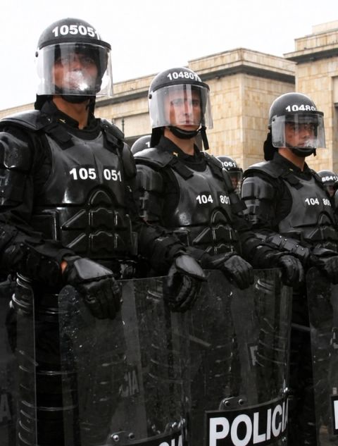 Uniformados antidisturbios con cascos, protección corporal y escudos policiales.
