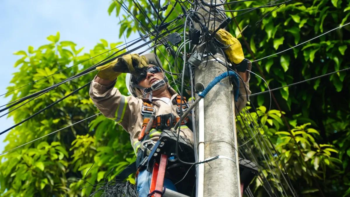 Un operario de Emcali trabaja en un poste de alumbrado público en Cali.