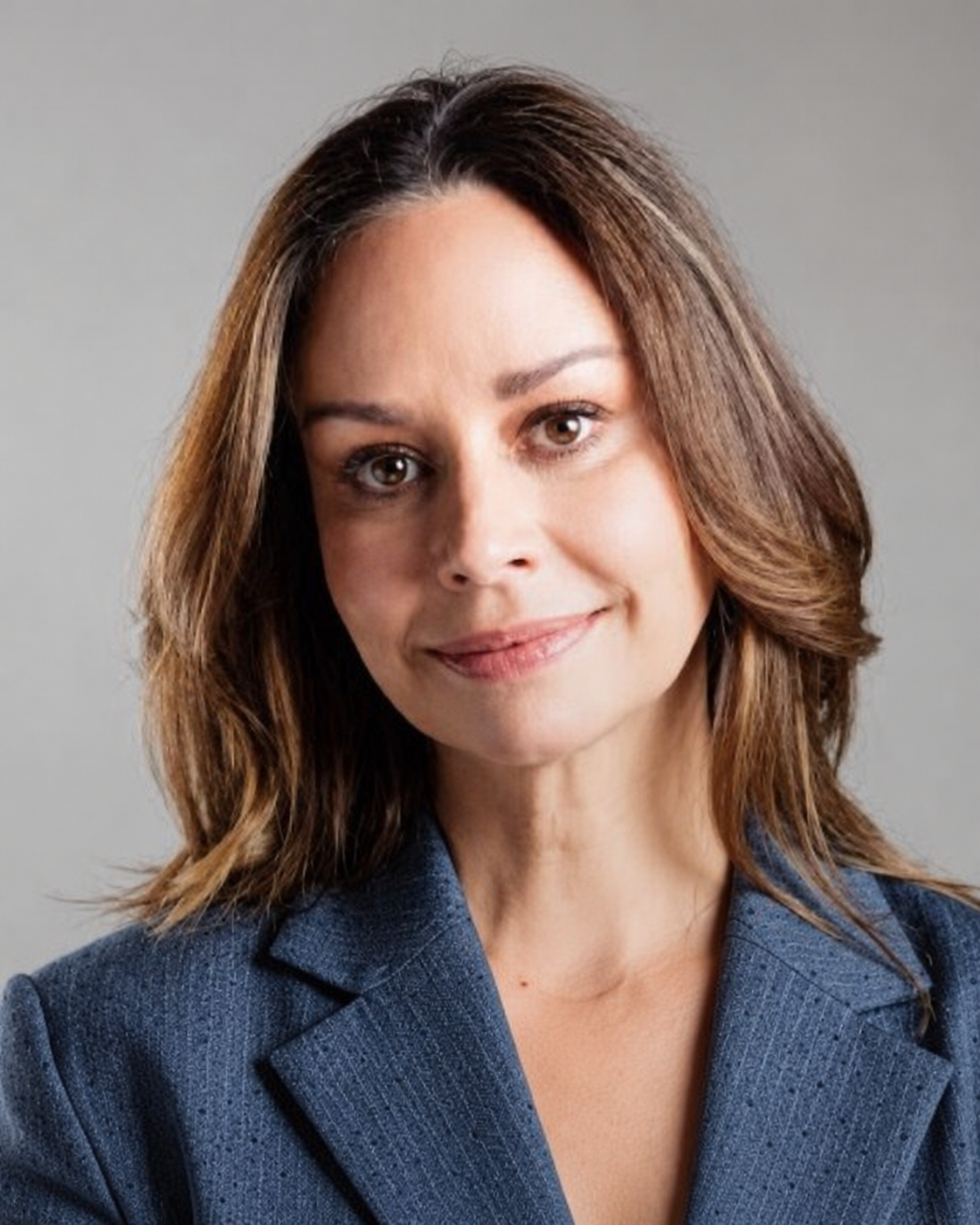 Retrato de María Claudia Tarazona, viuda de Miguel Uribe Turbay, con chaqueta azul y fondo gris.