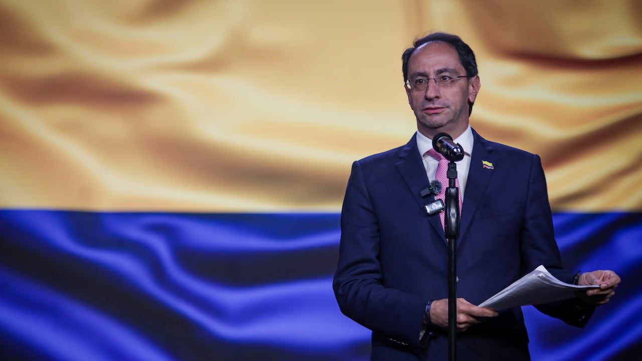 José Manuel Restrepo habla en un atril frente a una bandera de Colombia.