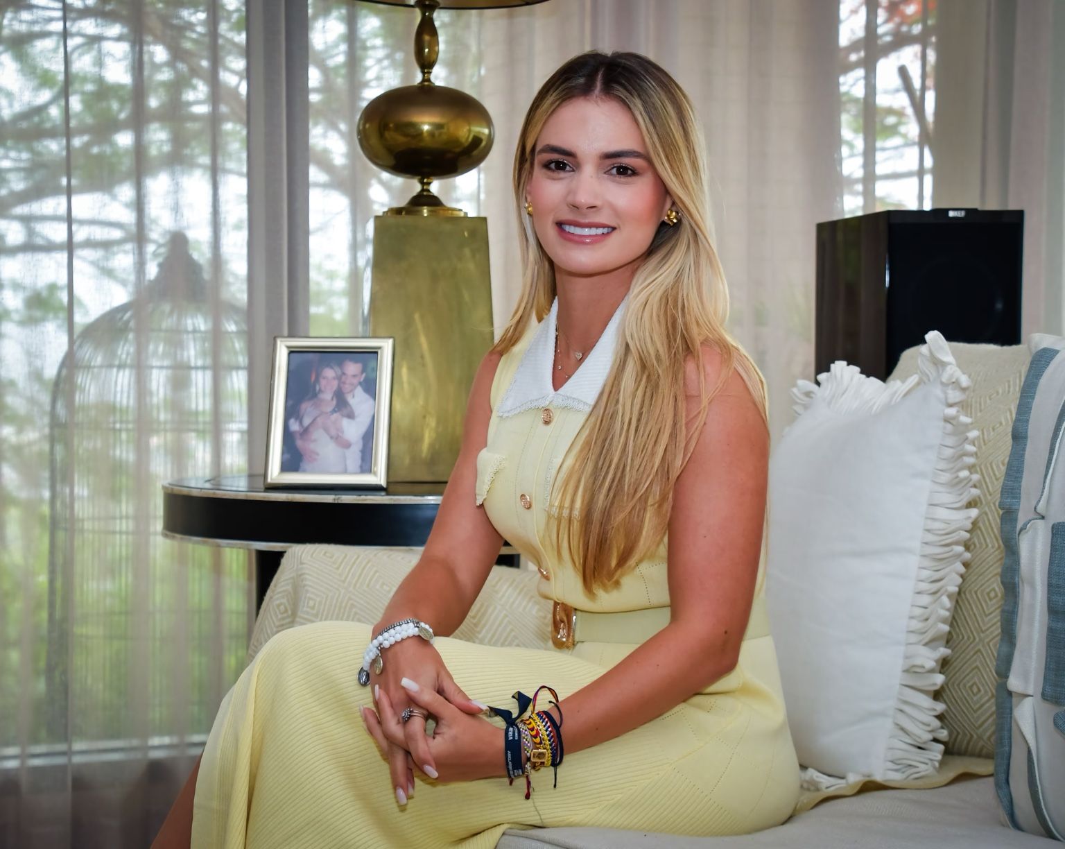 Ana Lucía Pineda sentada en un sofá, con vestido amarillo claro.
