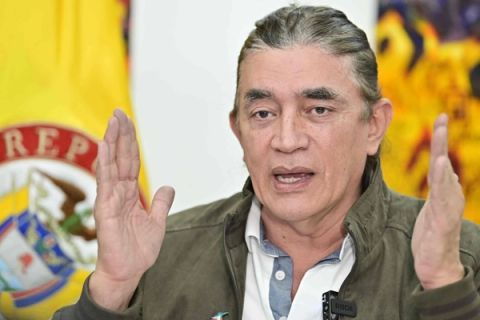 Gustavo Bolívar habla con las manos levantadas frente a banderas de Colombia.