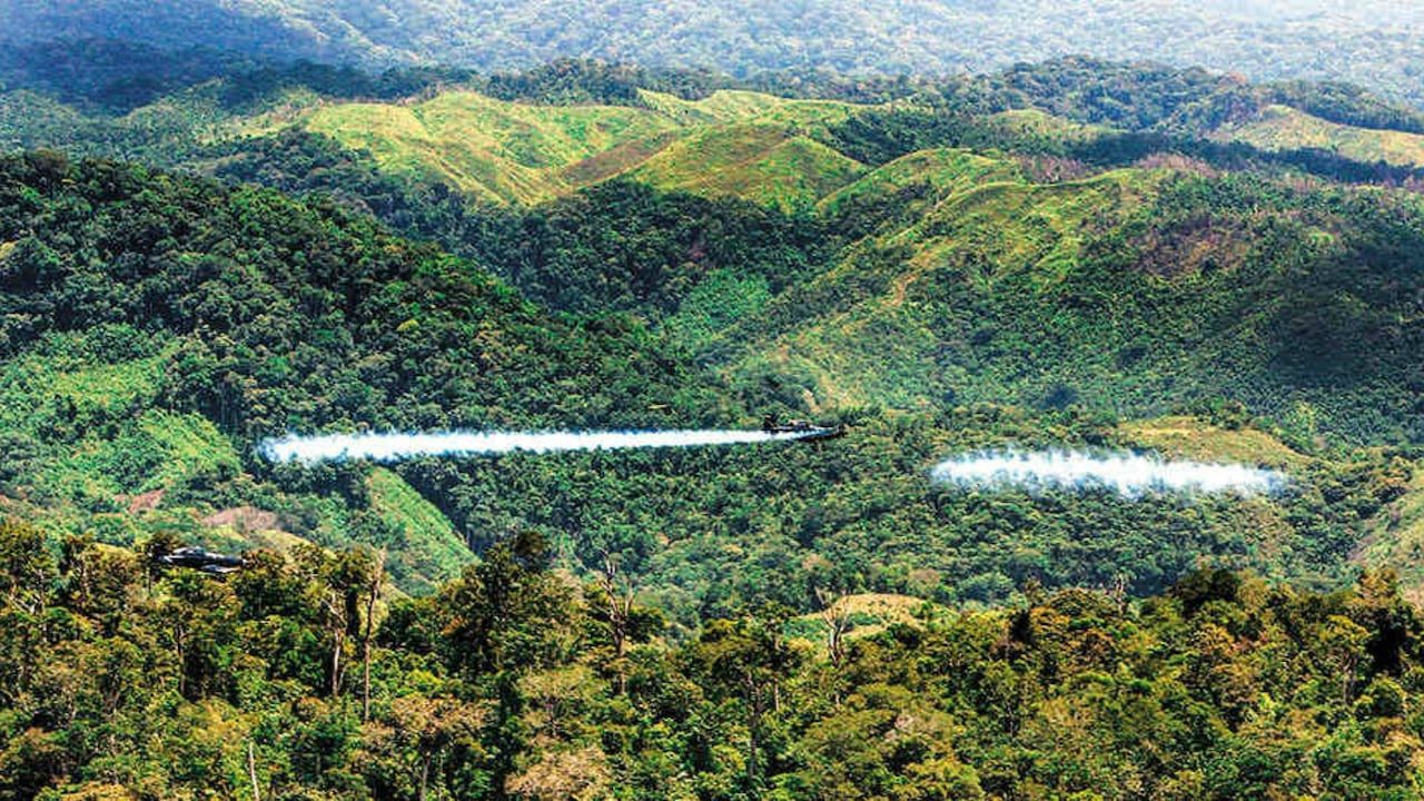 Aeronaves realizan aspersión aérea sobre una zona montañosa con vegetación.