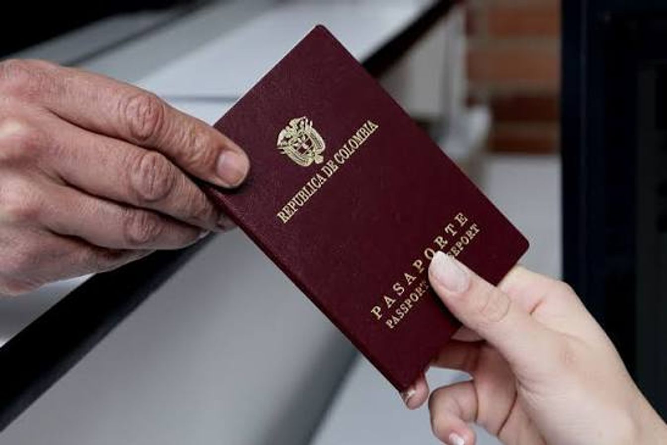 Dos personas sostienen un pasaporte colombiano.