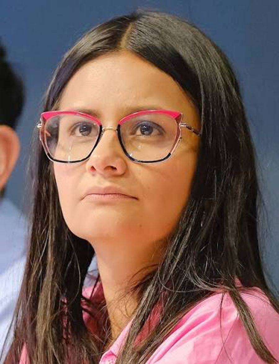 Angie Rodríguez con gafas de borde rosa y camisa rosa.