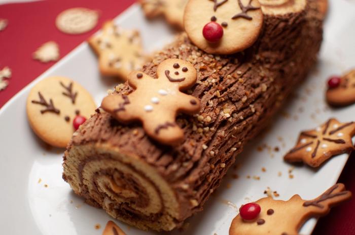 A yule log surrounded by gingerbread biscuits.