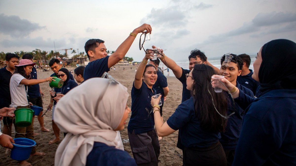 Peserta RSM bekerja sama dalam permainan estafet air saat team building di pantai.