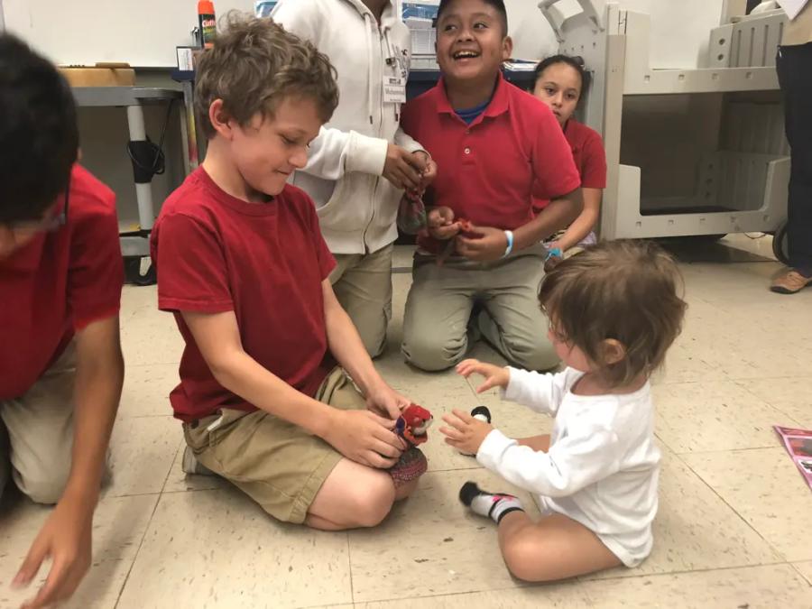 A student playing on the floor with a toddler