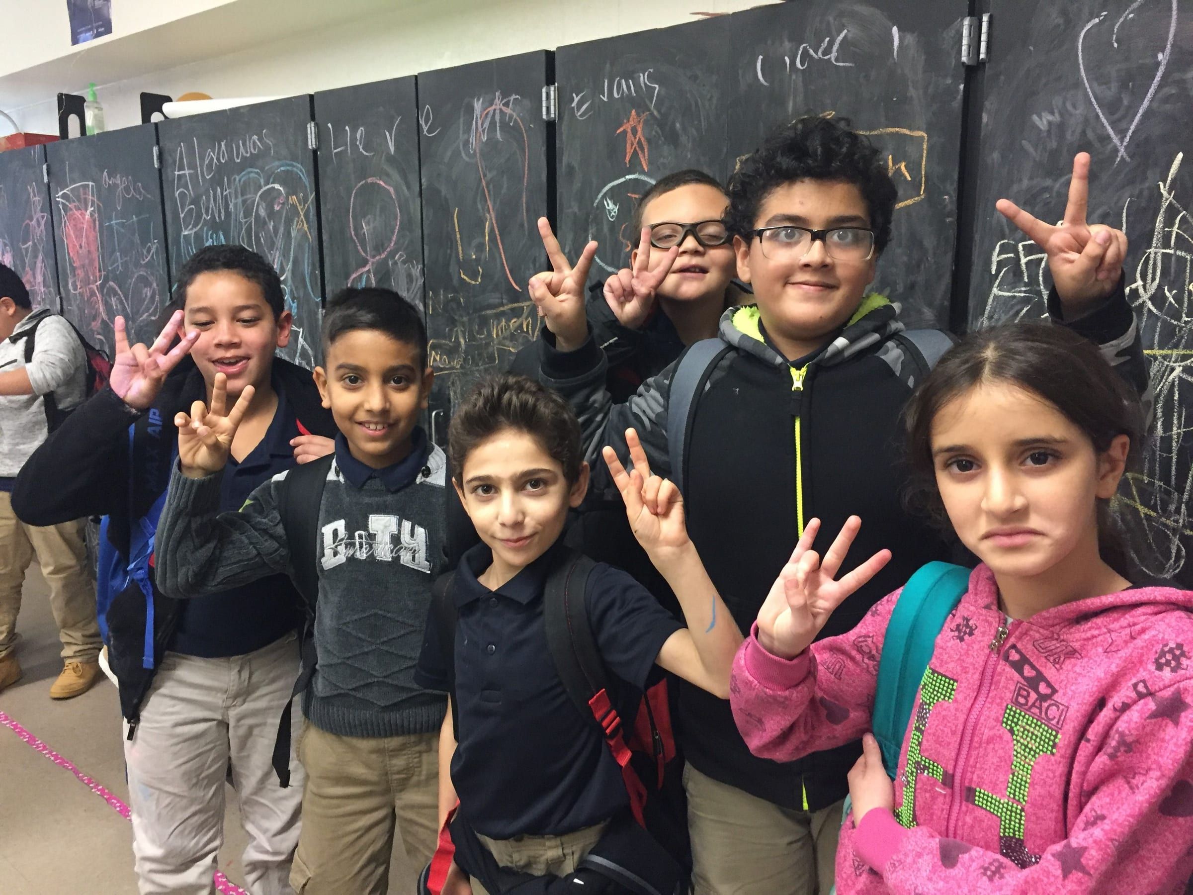 Smiling students in a school hallway making peace signs