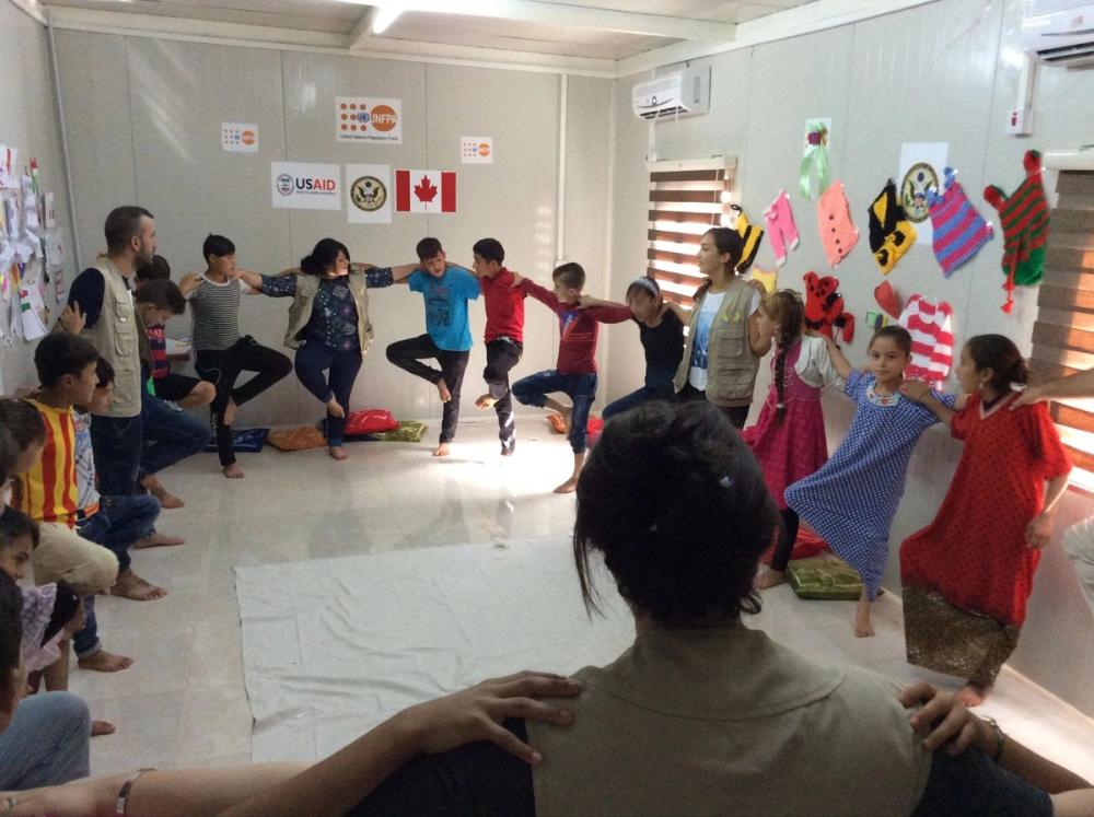 Children and our team dancing in a circle inside a camp classroom