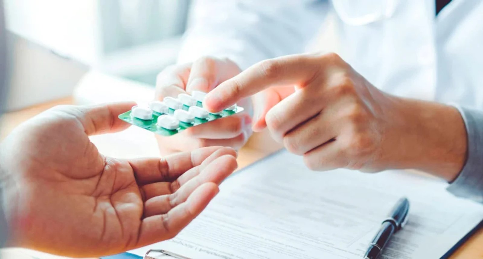 Médico entregando un envase de medicamento a un paciente durante una consulta.