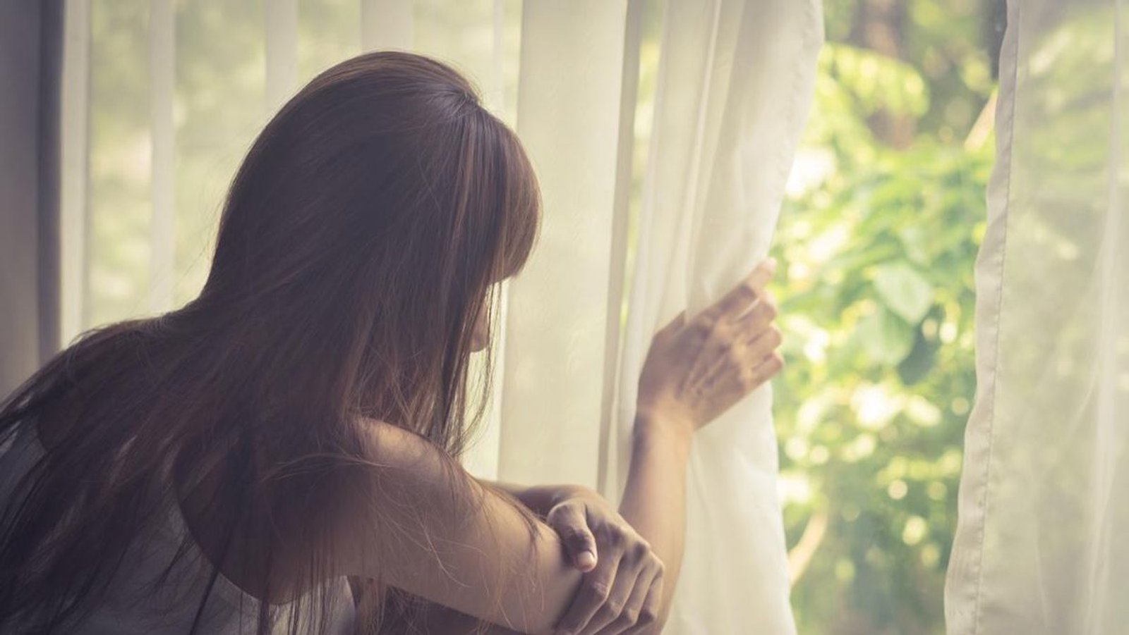 Persona mirando a través de una ventana en gesto pensativo, evocando los efectos del aislamiento prolongado sobre la cognición.