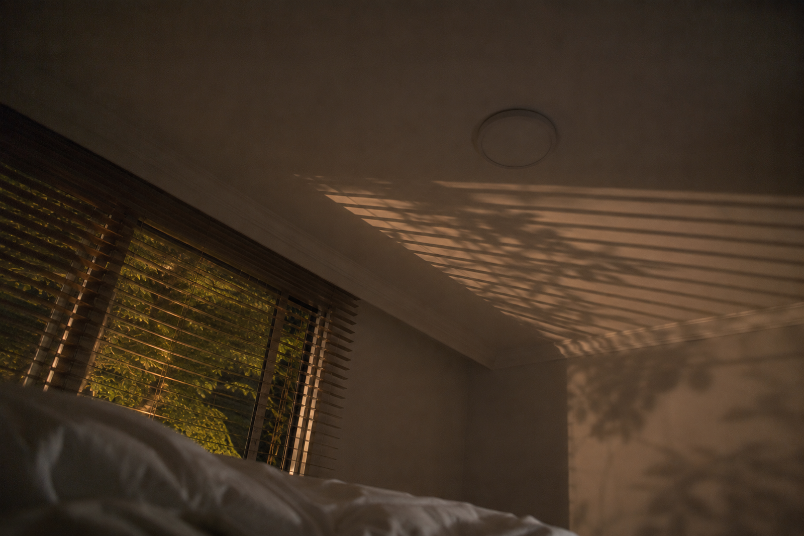 Techo de una habitación a oscuras con las sombras de la persiana proyectadas por la luz de la calle