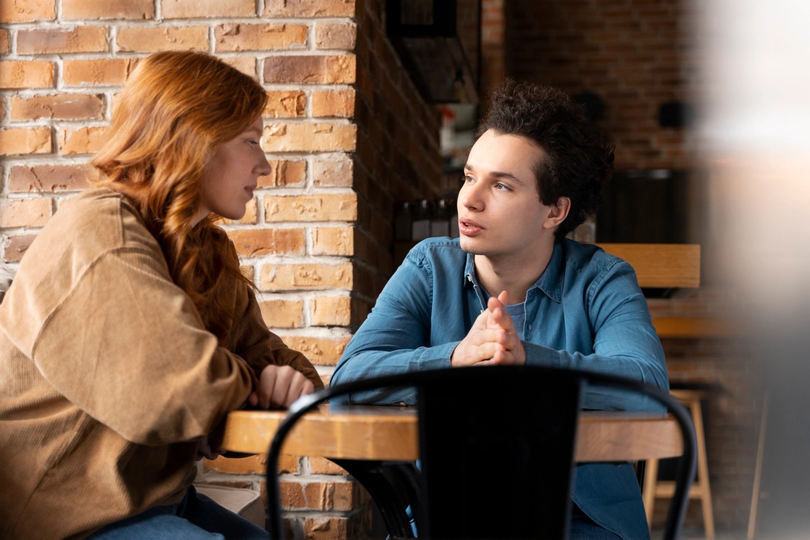 Dos amigos sentados frente a frente sosteniendo una conversación íntima y seria.