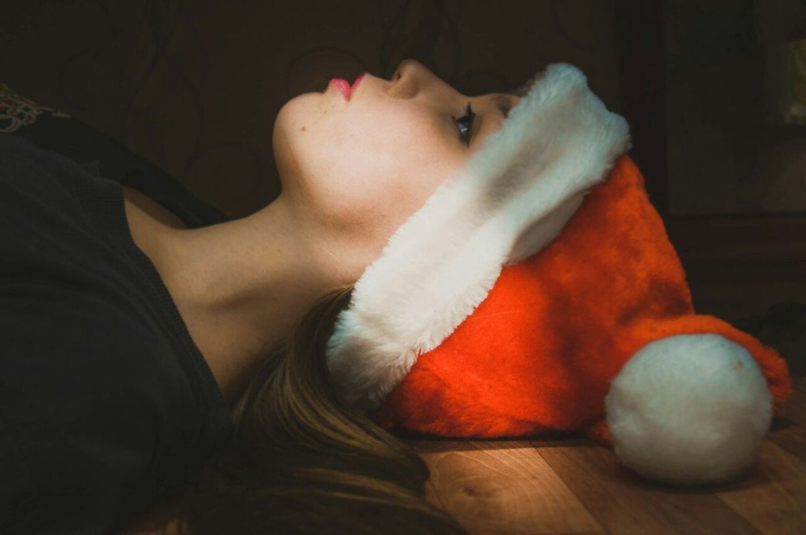 Mujer joven con gorro navideño en actitud melancólica, contraste entre el ánimo festivo esperado y la vivencia interna en diciembre.