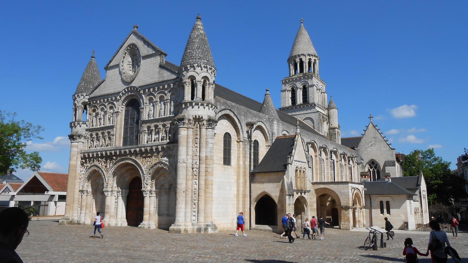 Fachada românica da igreja de Notre-Dame-la-Grande, em Poitiers, numa praça com pessoas