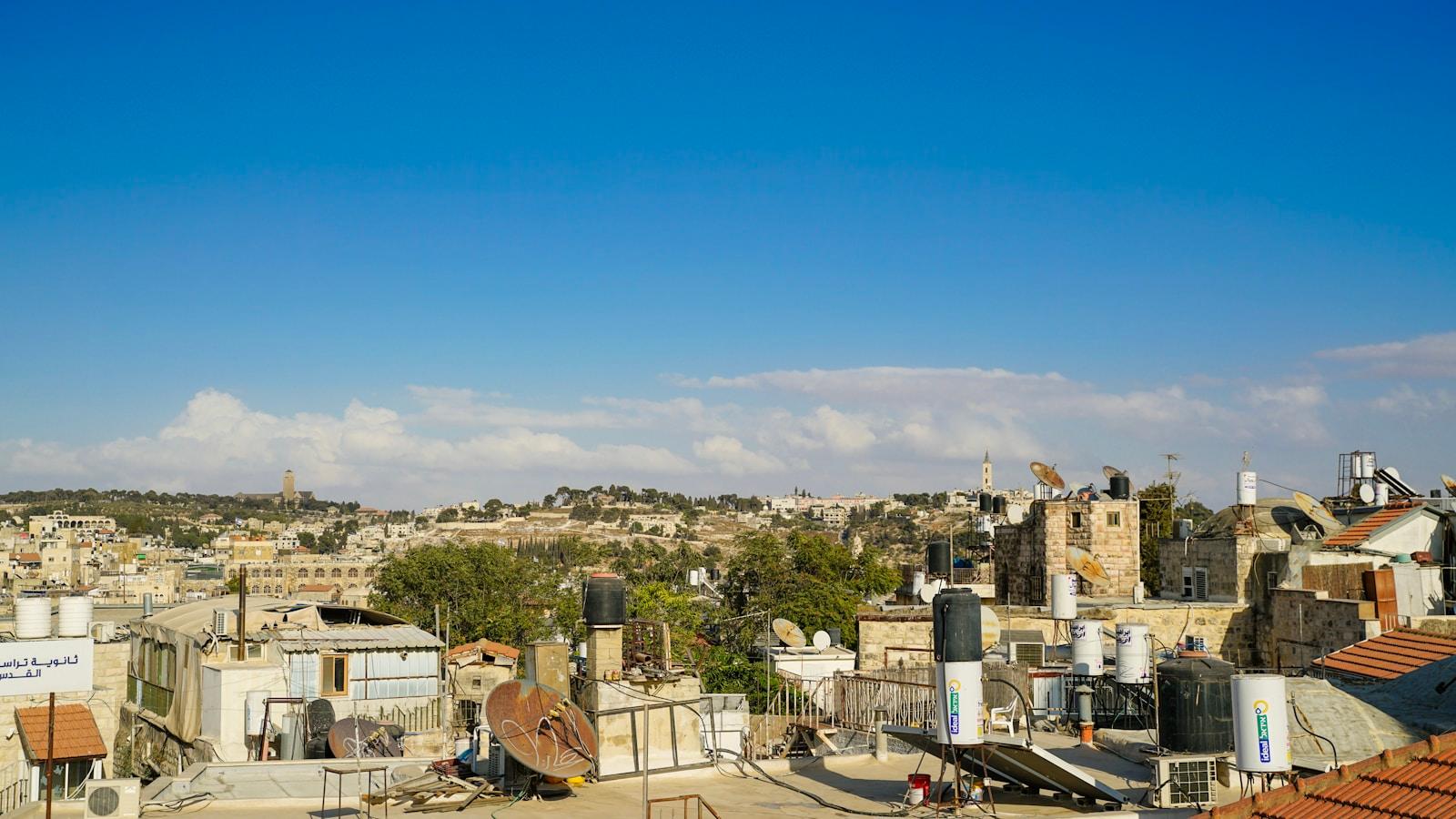 Telhados da Cidade Velha de Jerusalém, com torres ao fundo, sob céu azul