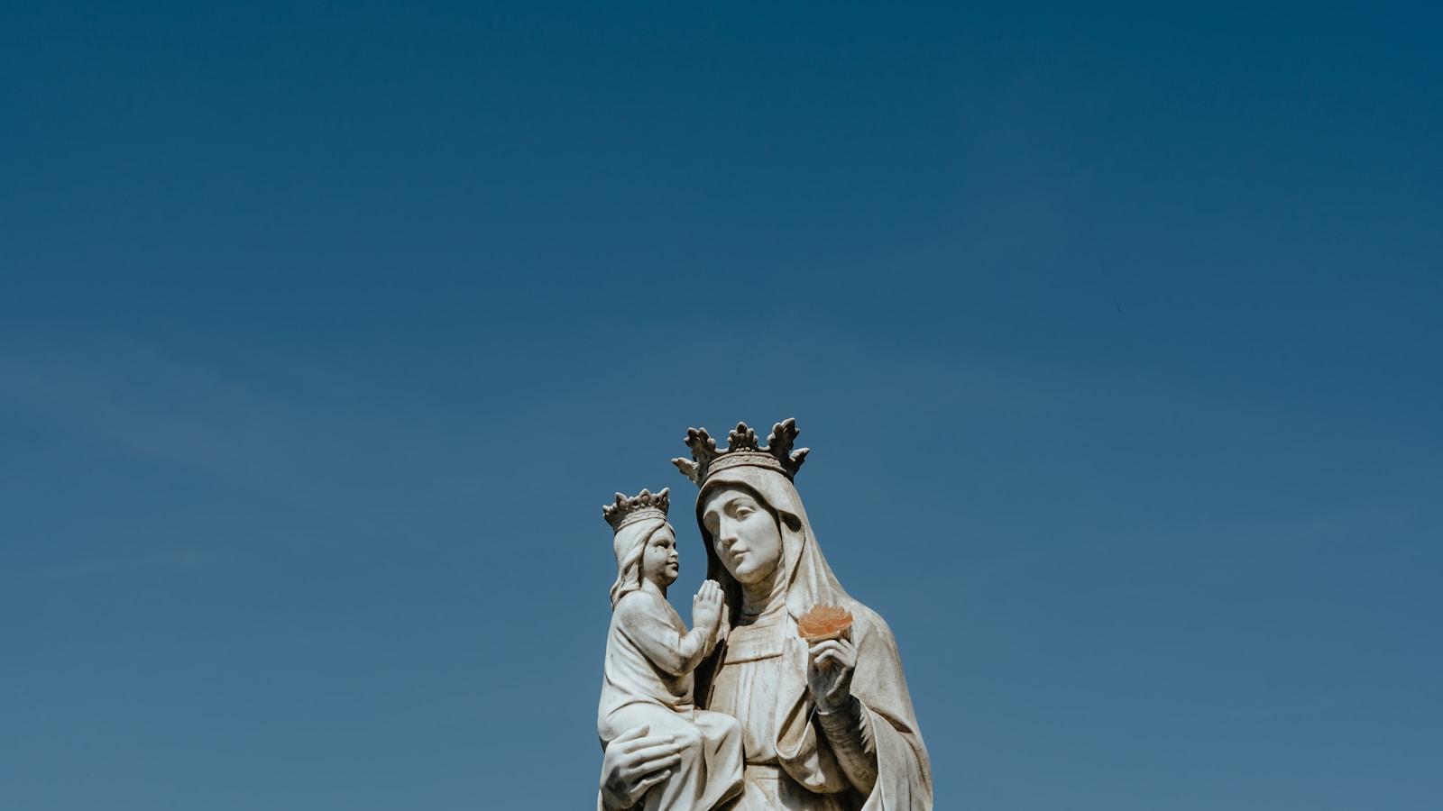 Estátua de Nossa Senhora coroada com o Menino Jesus, contra o céu azul