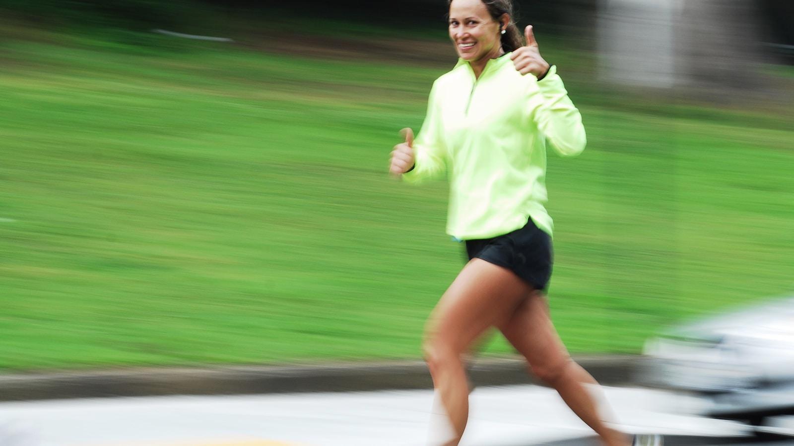 Mulher correndo sorridente com blusa amarela, em movimento
