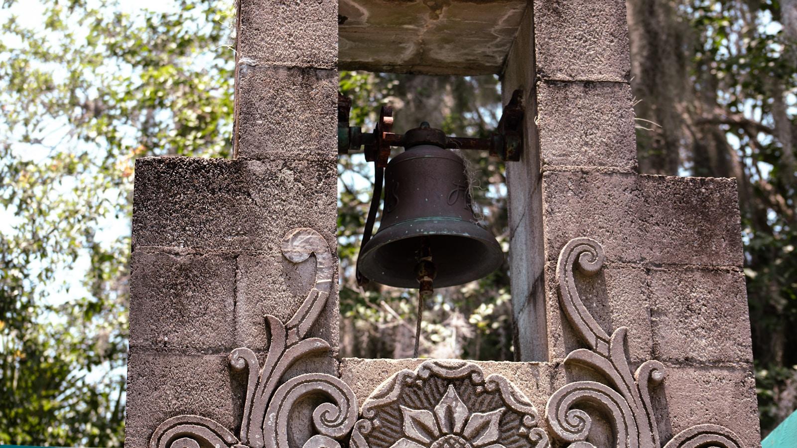 Sino de bronze num campanário de pedra com relevos decorativos