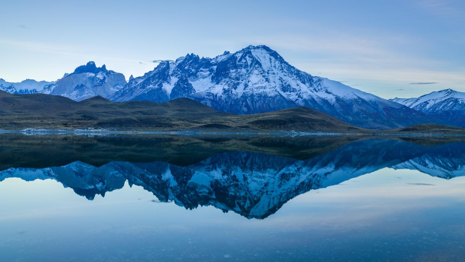 Montanhas com neve dos Andes chilenos refletidas num lago ao amanhecer