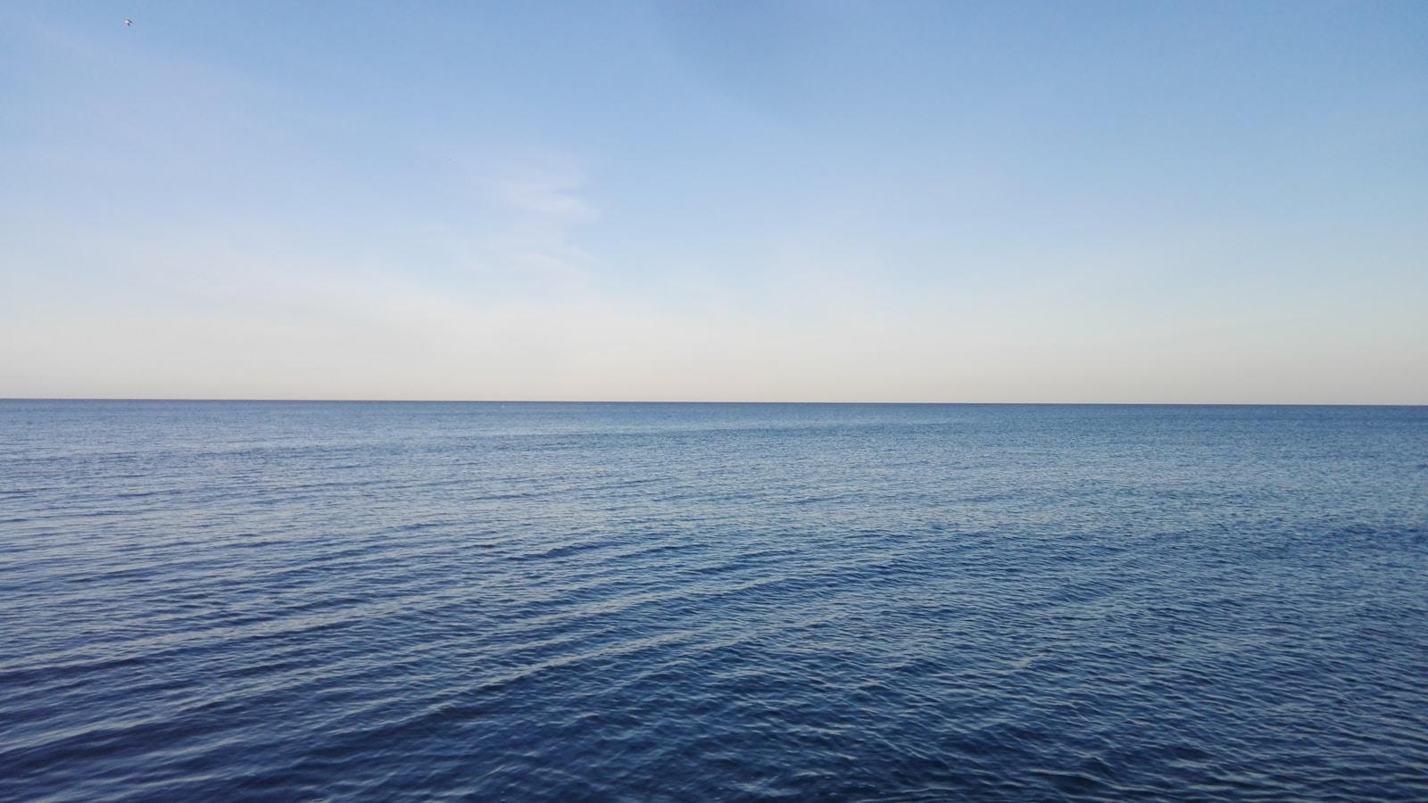 Mar calmo e azul até o horizonte, sob céu claro