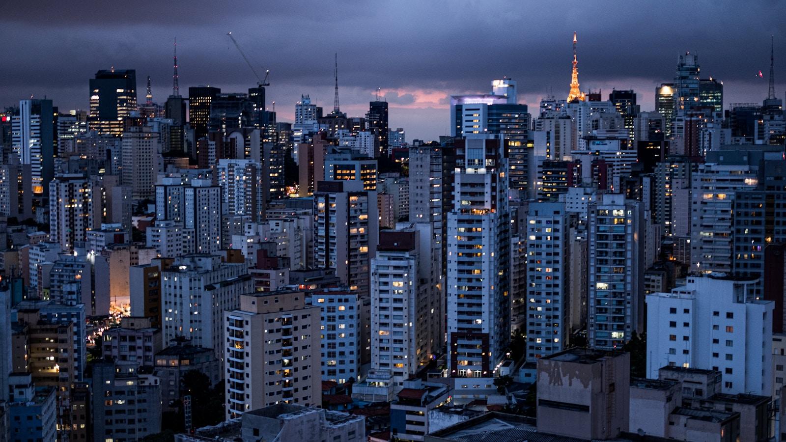 Prédios do centro de São Paulo ao anoitecer, com luzes acesas