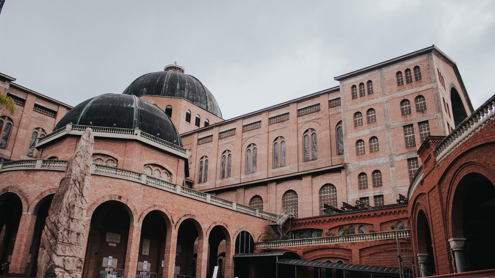 Basílica de Nossa Senhora Aparecida, com suas cúpulas e paredes de tijolo, sob céu nublado