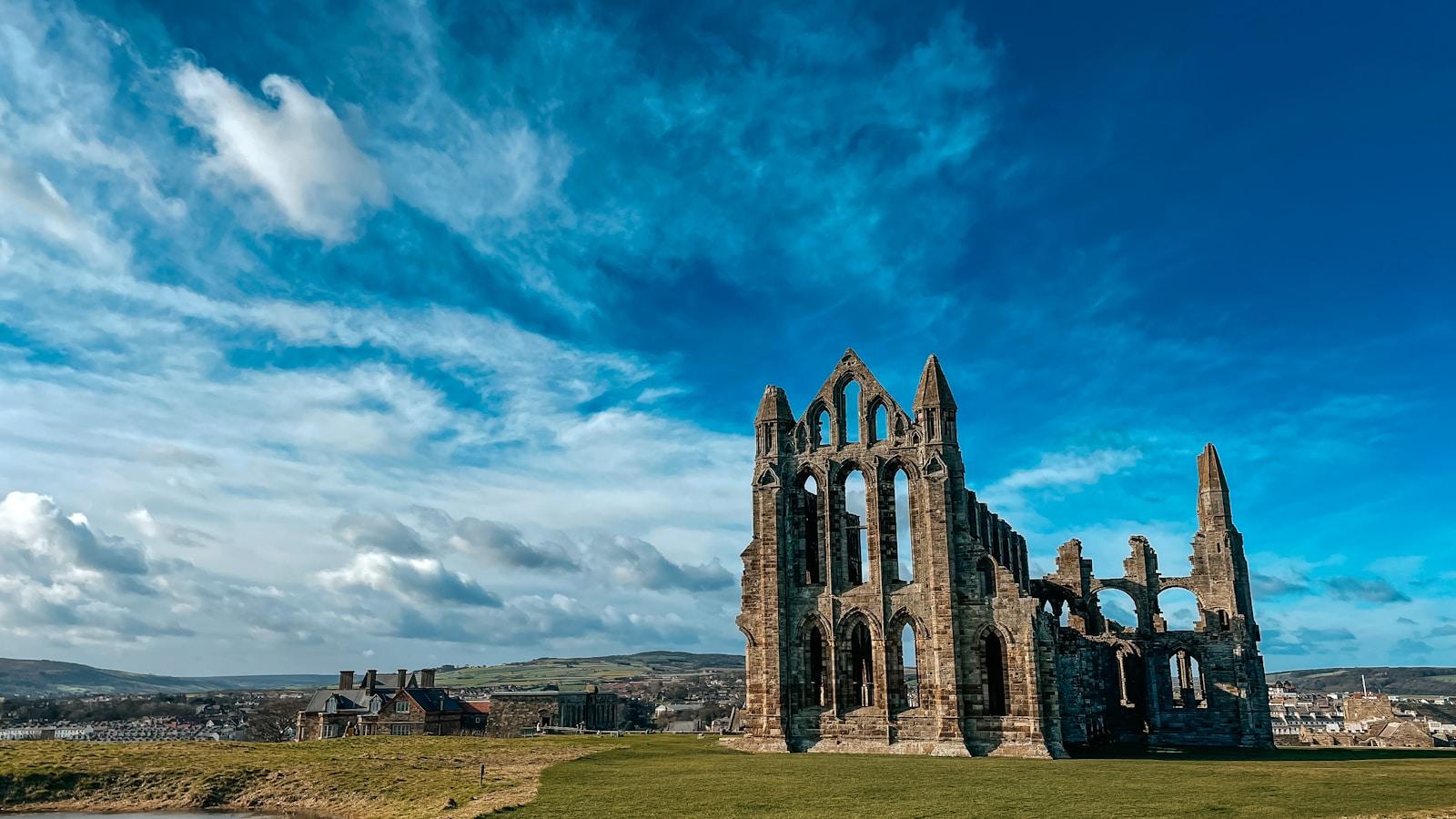 Ruínas góticas da Abadia de Whitby sobre a colina, sob céu azul com nuvens