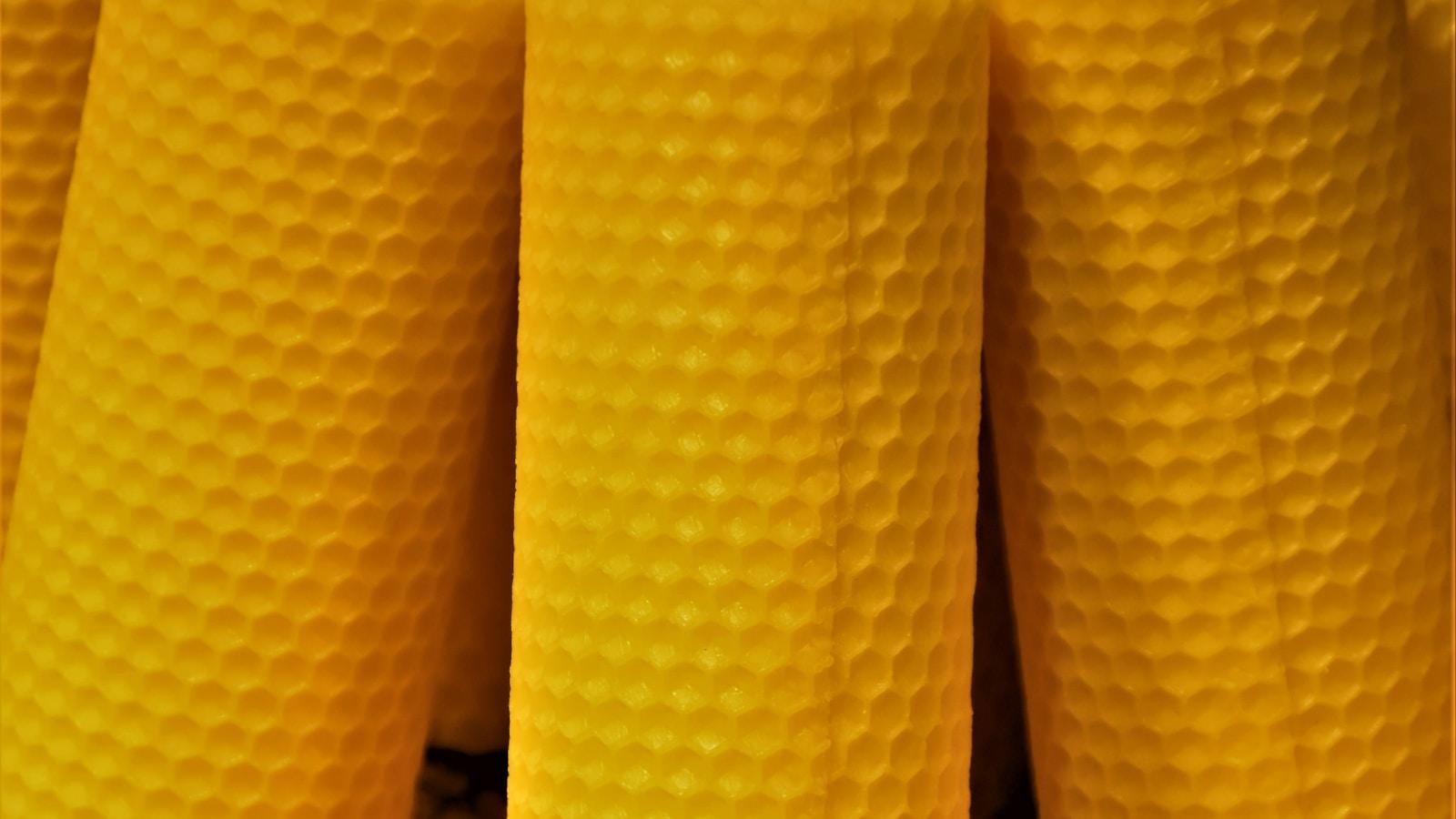 Velas de cera de abelha enroladas, amarelas, com a textura hexagonal do favo