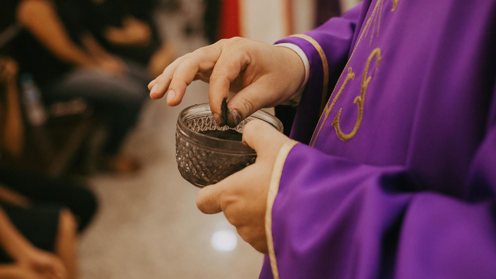 Sacerdote de paramento roxo segurando um recipiente com cinzas