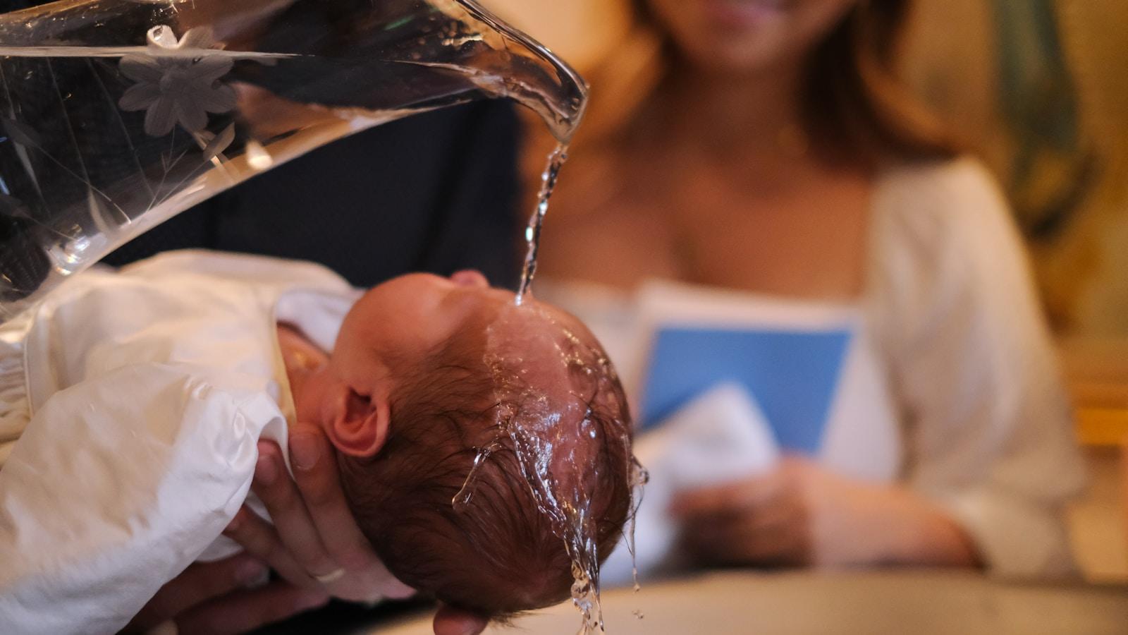 Água sendo derramada sobre a cabeça de um bebê no batismo