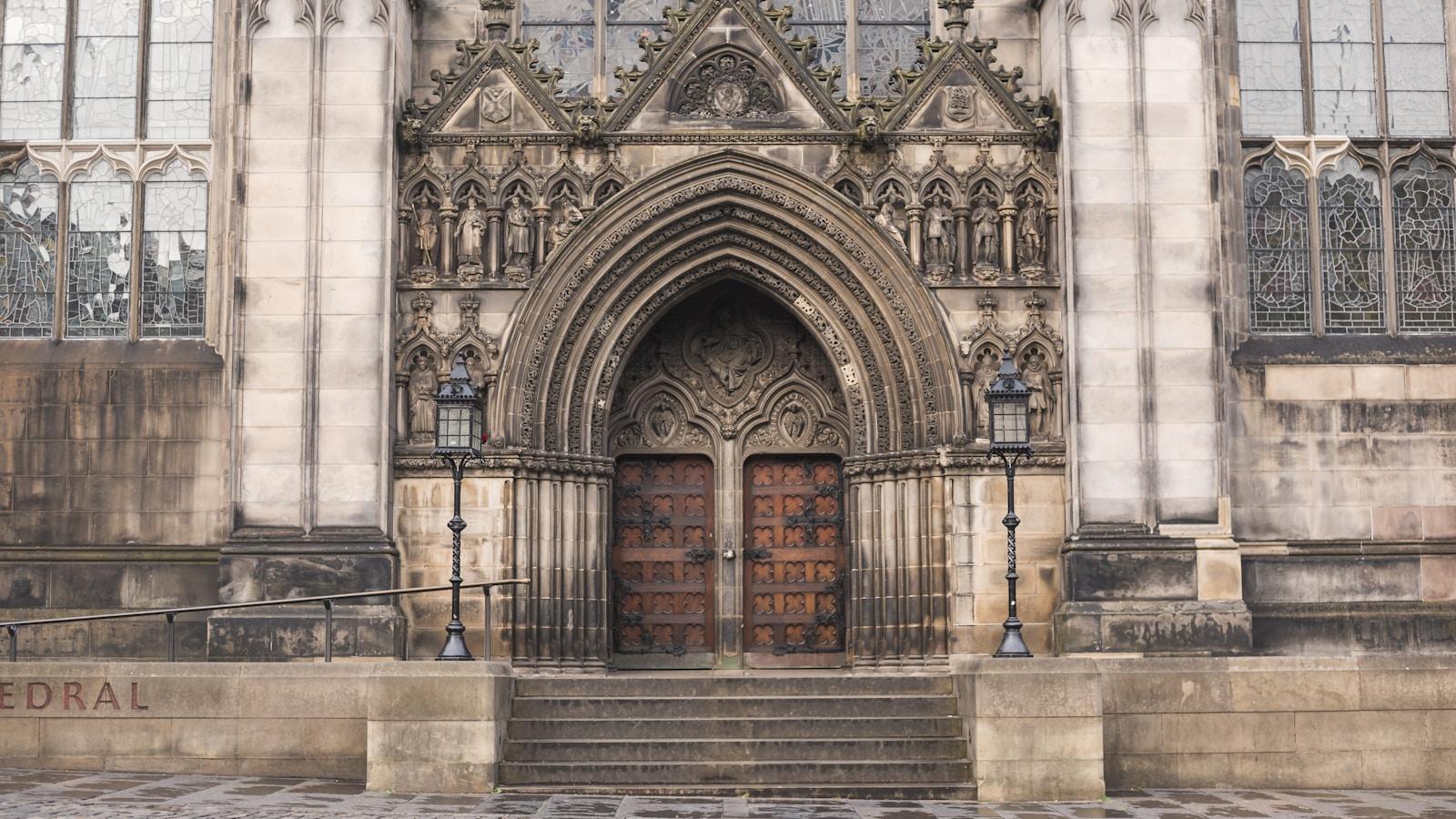 Portal gótico de uma catedral com portas de madeira fechadas e escadaria de pedra