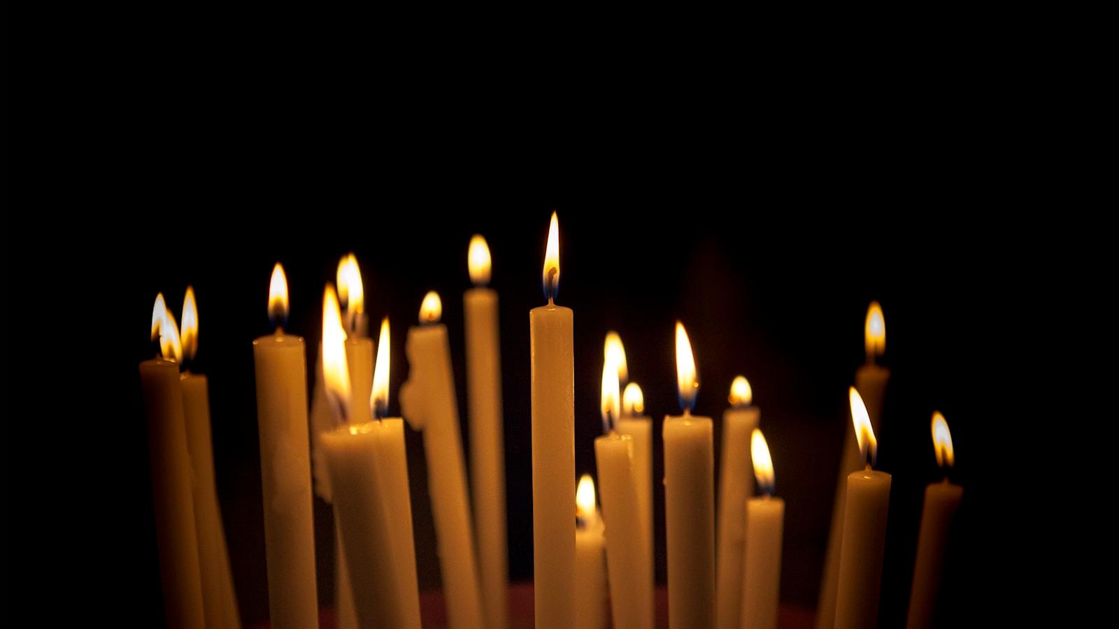 Velas finas acesas em grupo, no escuro