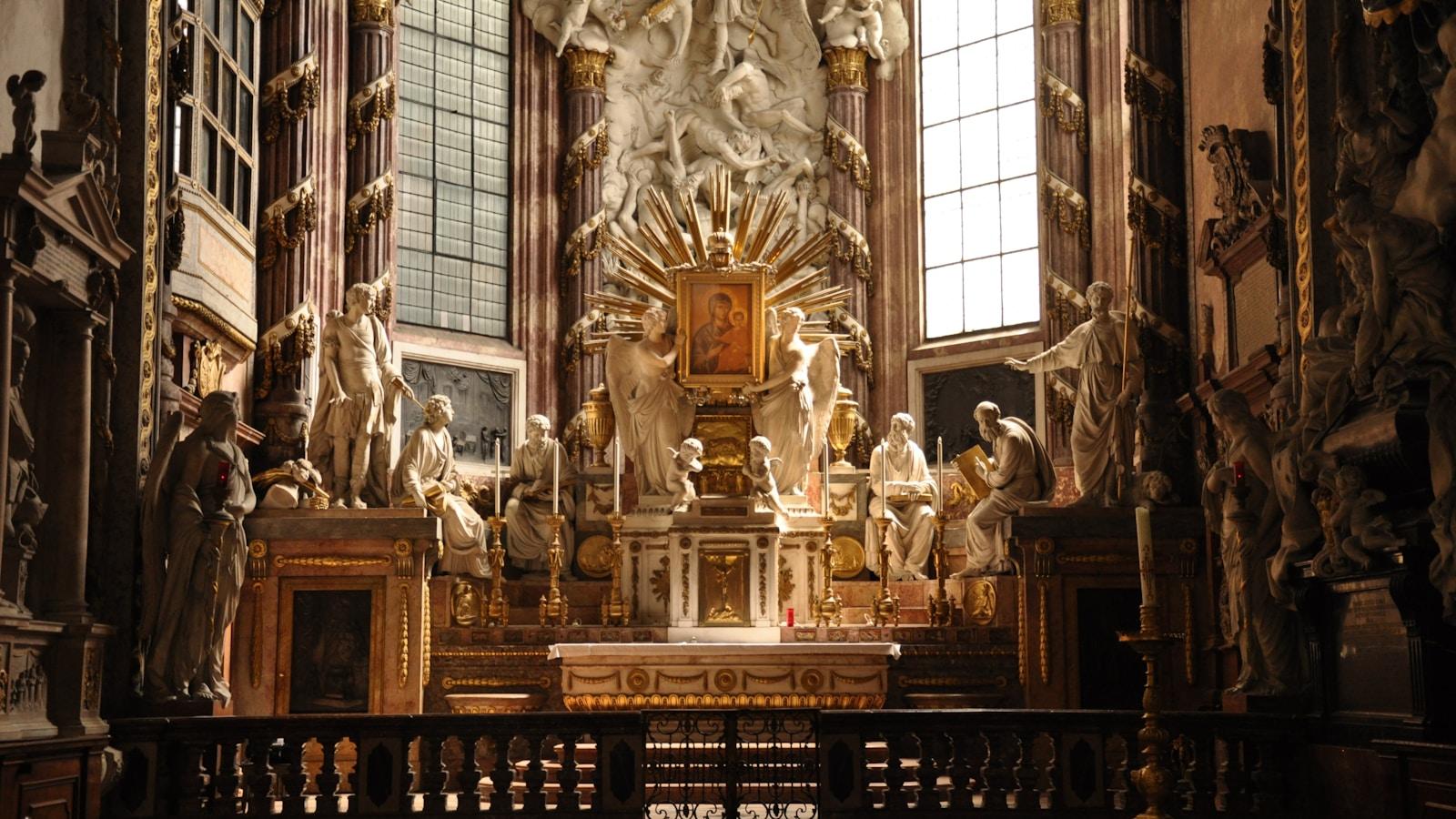 Altar barroco com esculturas brancas e douradas, iluminado por janelas altas