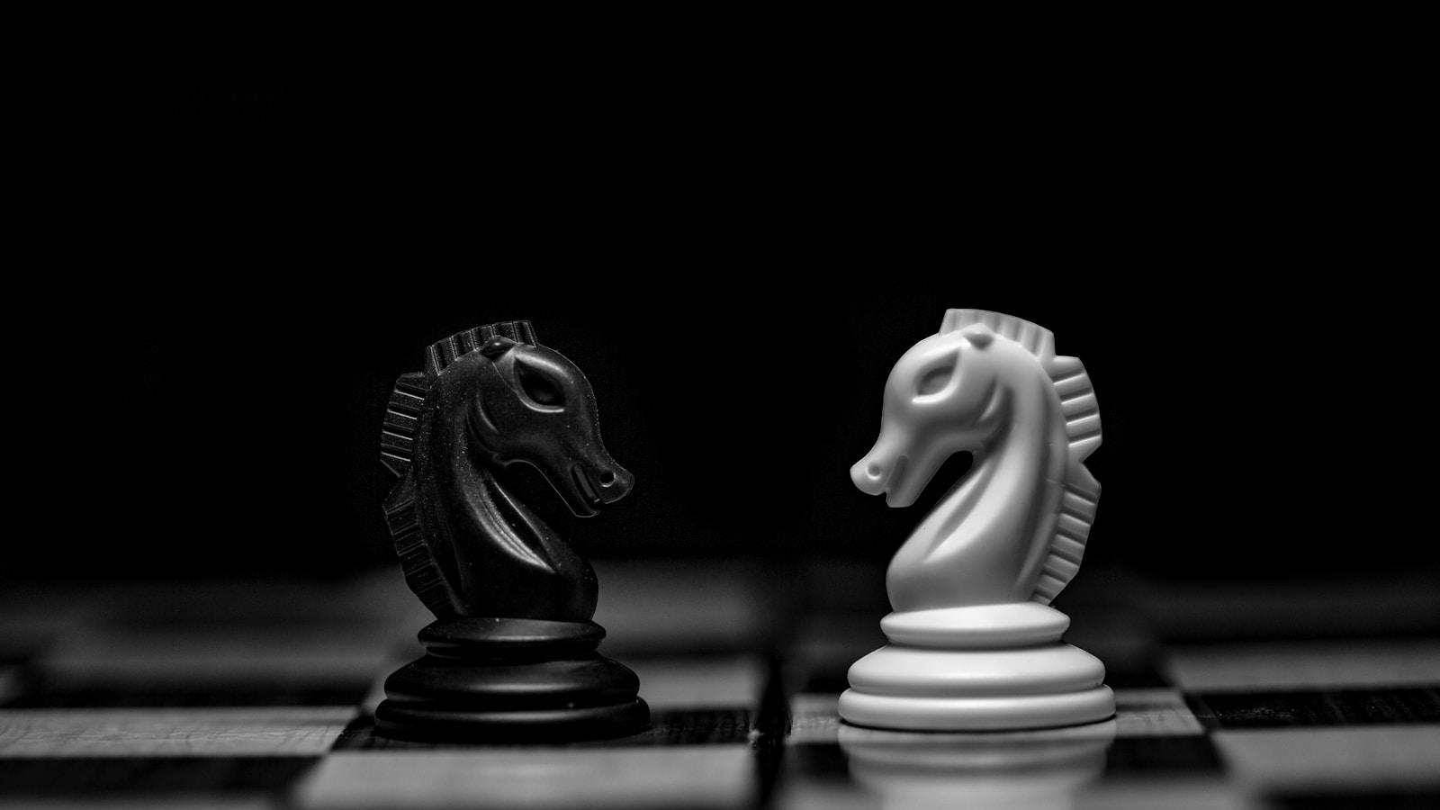 Dois cavalos de xadrez, um preto e um branco, frente a frente no tabuleiro