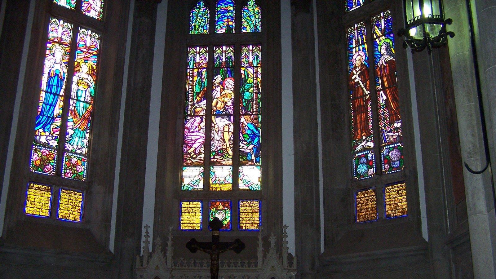 Vitrais coloridos e um crucifixo na capela-mor de uma igreja