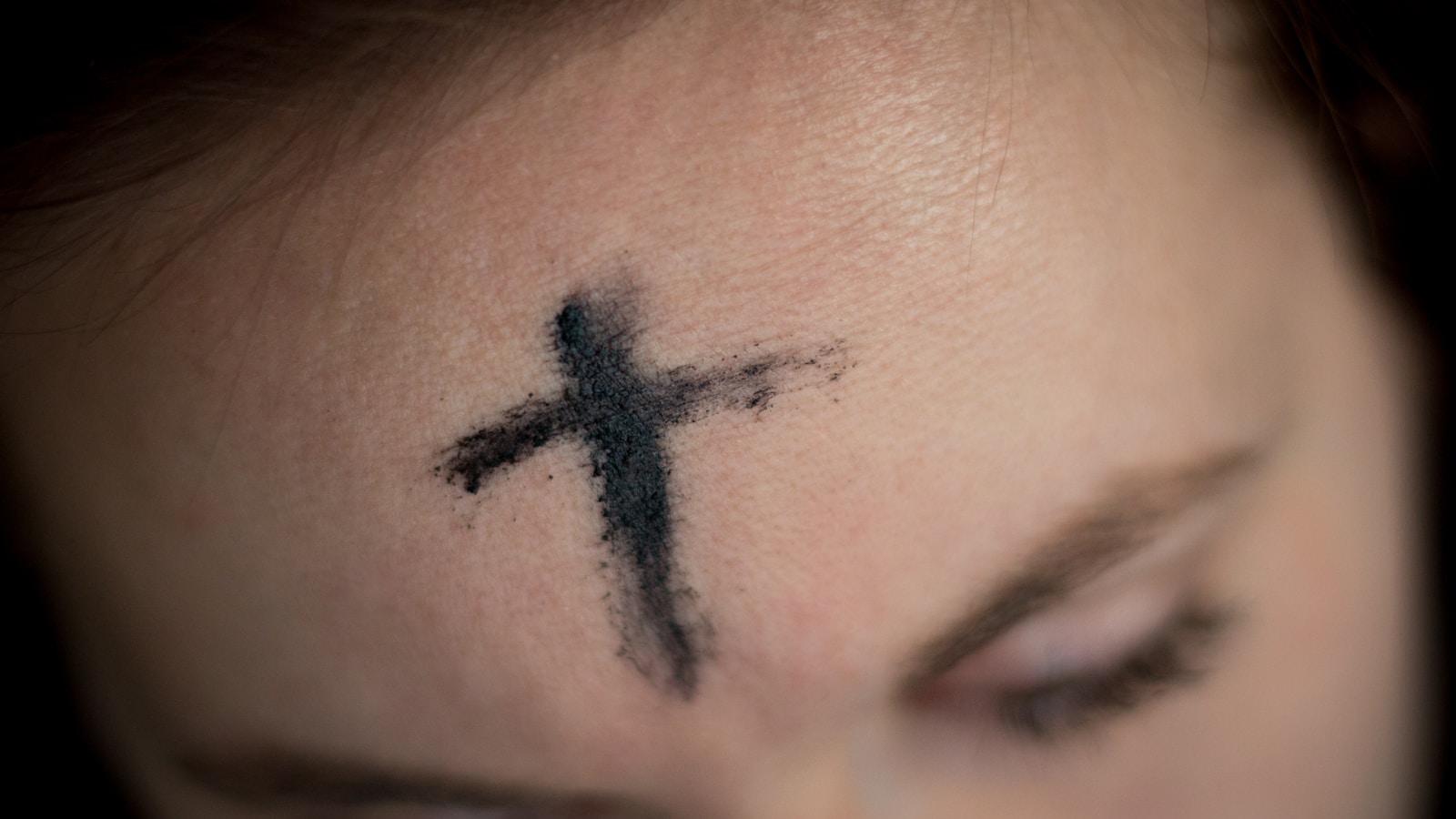 Cruz de cinzas marcada na testa de uma mulher, em close