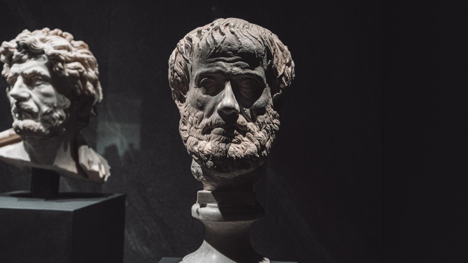 Busto de mármore de Aristóteles, com barba e cabelos encaracolados, em sala escura de museu