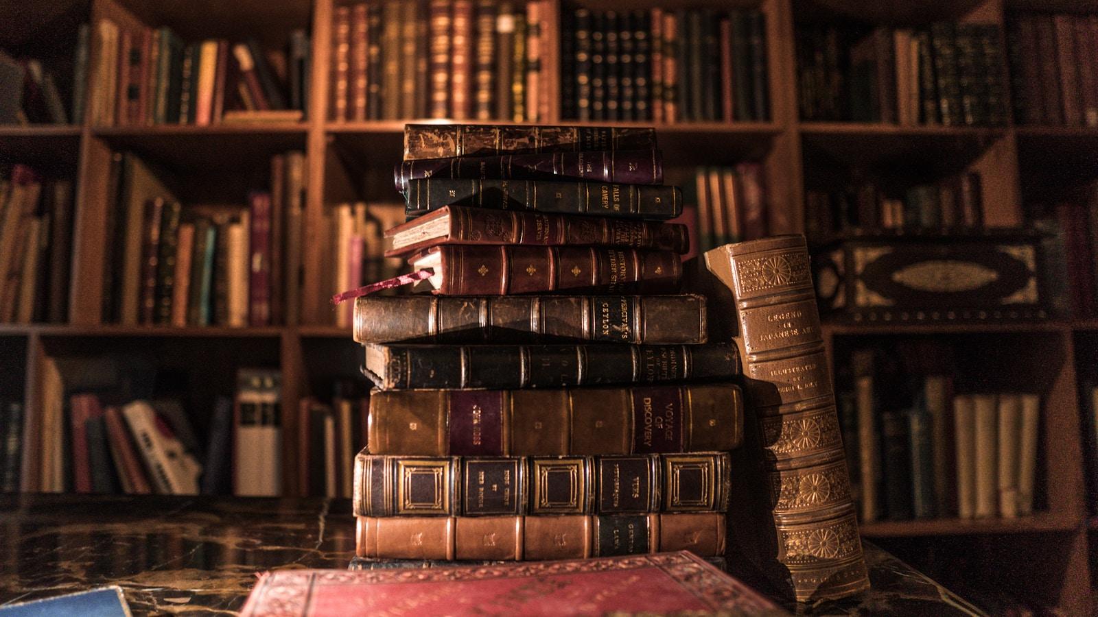 Pilha de livros antigos encadernados em couro, diante de uma biblioteca