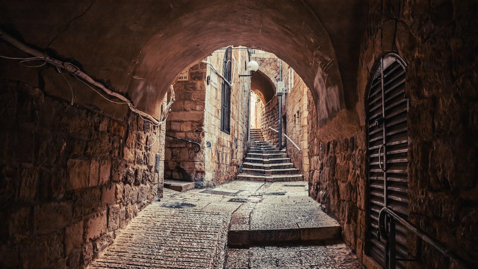 Passagem em arco de pedra numa rua antiga de Jerusalém, com escadas ao fundo